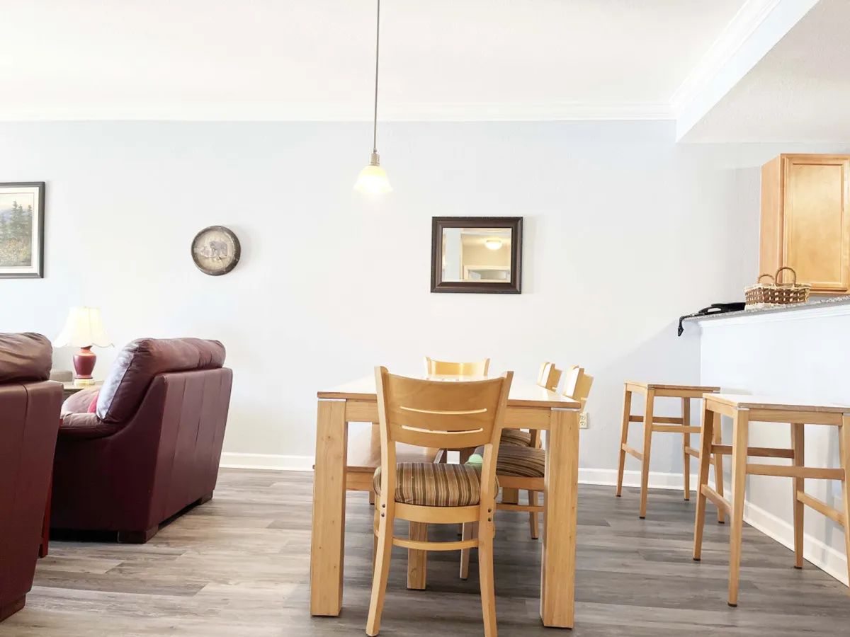 This photo focuses on a dining area adjacent to a plush living room, with a dining table ready for meals or board games. Decorative wall art and soft, comfortable couches add warmth and character, and the open-concept layout allows clear sight lines throughout the space.