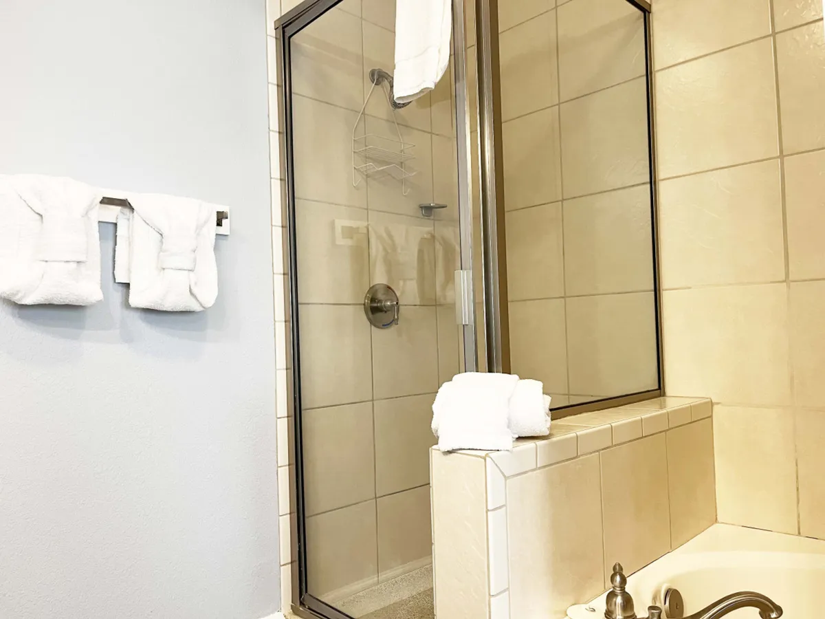 A tranquil bathroom scene with a modern shower enclosure, separate bathtub, and neatly stacked towels, evoking a spa-like experience. The room is designed for relaxation, ideal for soaking away stress or enjoying a refreshing shower.