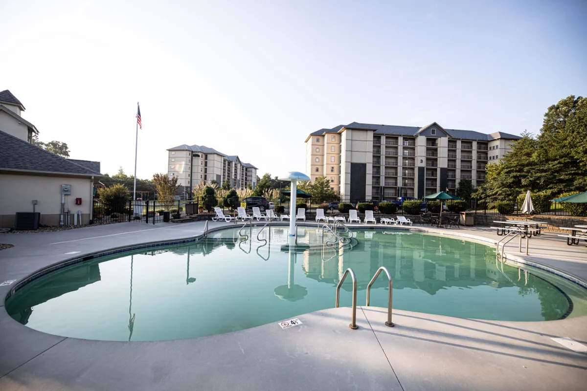 An inviting outdoor swimming pool surrounded by lounge chairs and adjacent buildings. The pool area is well-maintained and positioned to capture sunlight, creating a welcoming spot for swimming, sunbathing, or relaxing during warm weather. The communal setting suggests opportunities for social gatherings and family fun.